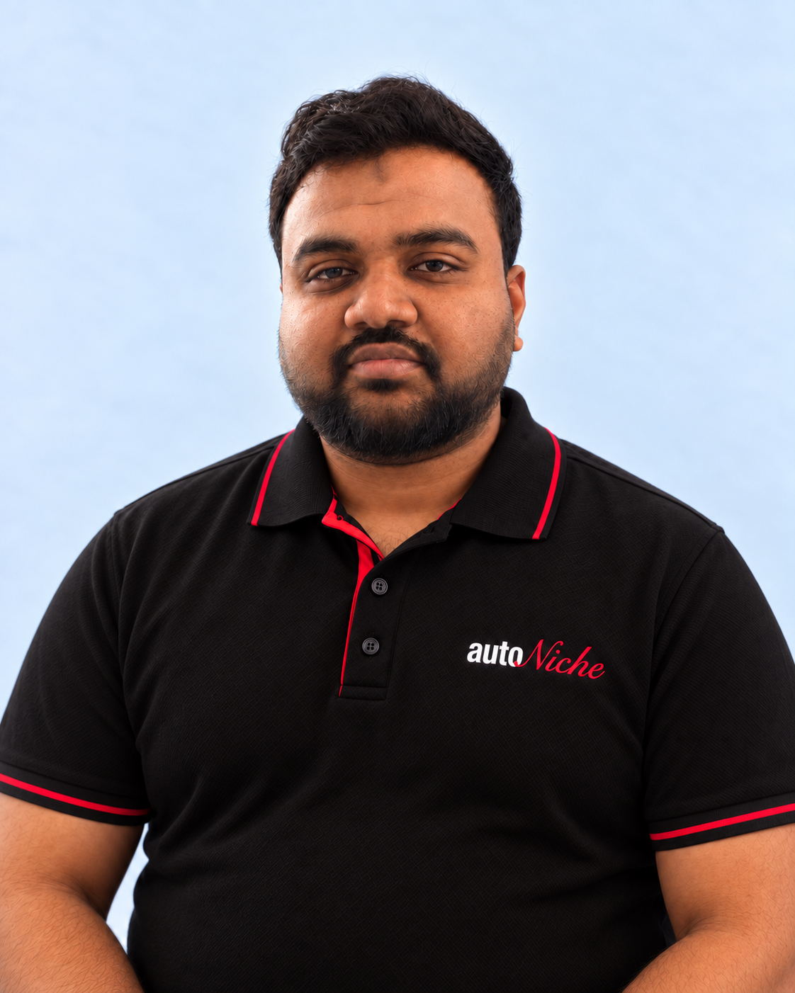 Yasser, AutoNiche Service Manager, wearing an AutoNiche polo against a pale blue studio background